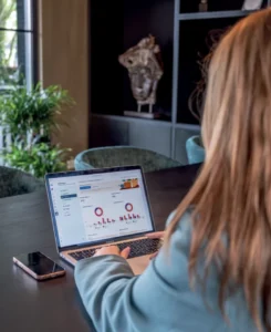 Person sitting at a dark table using a laptop to view business analytics dashboards with charts and graphs on screen